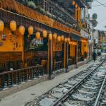 Lantern-lit café along Hanoi’s Train Street, with railway tracks running beside wooden balconies.